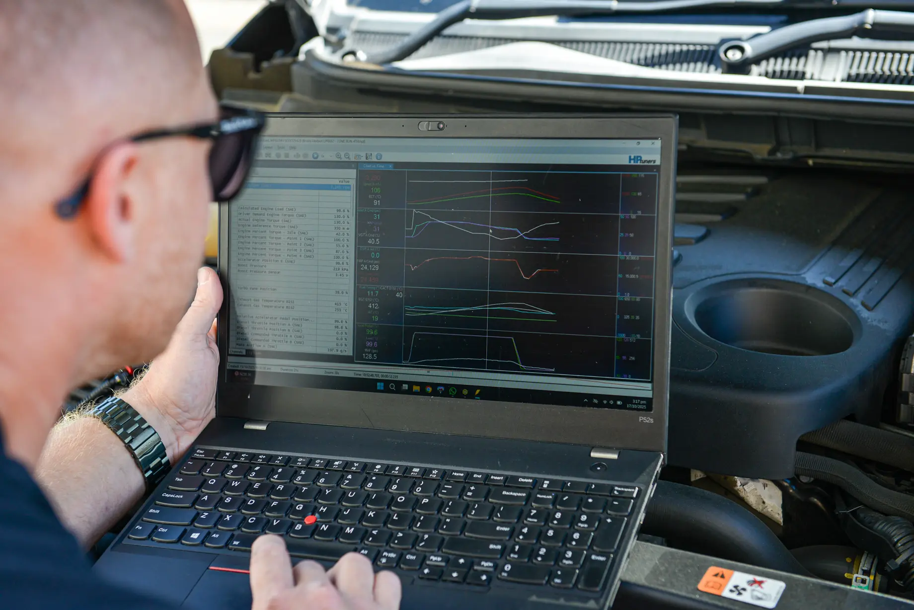 Mechanic using a diagnostic laptop connected to a vehicle for engine tuning and performance analysis